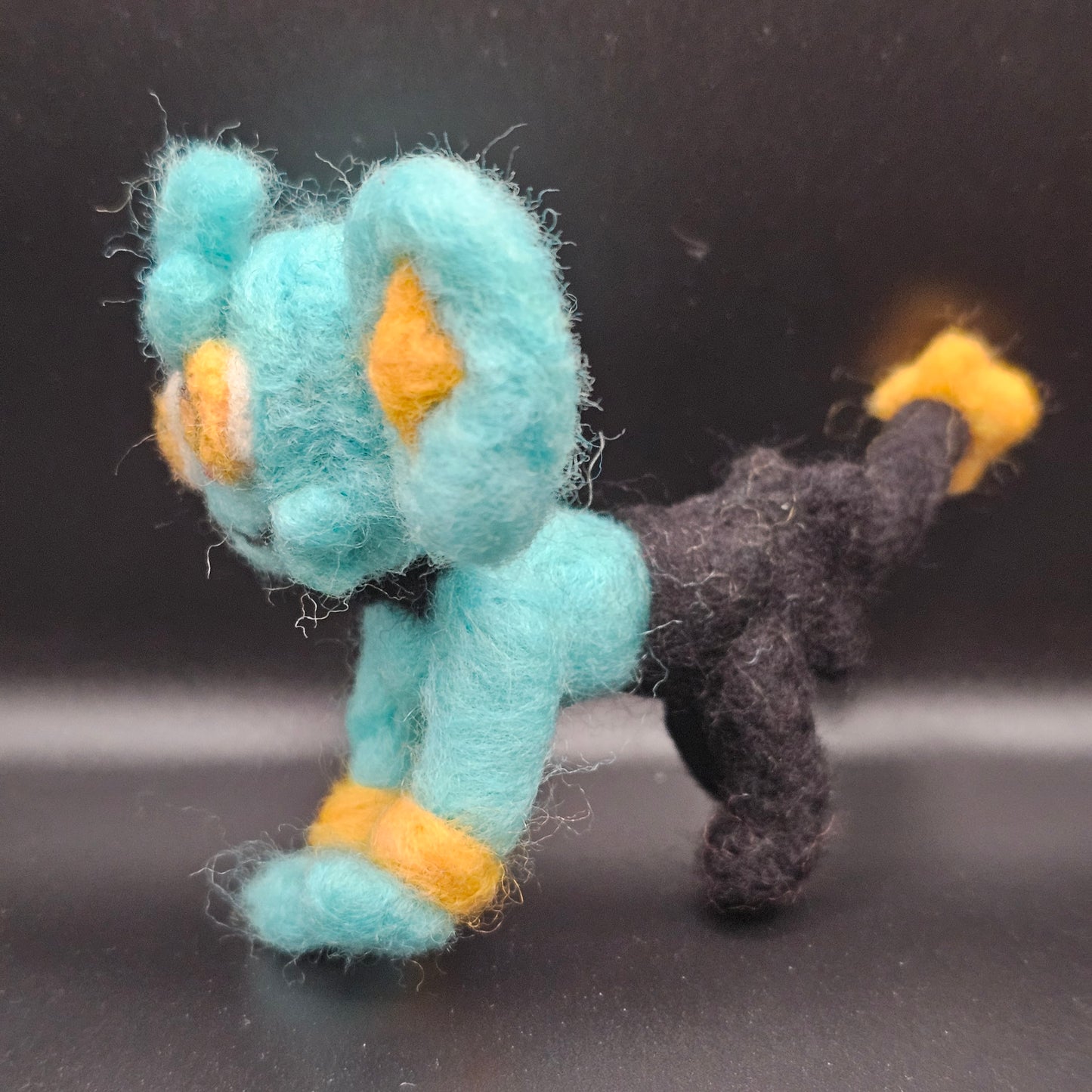 Skitty is a a pink cat with tall ears and a tail that looks sort of like a balloon on a string, with more balloons hanging from it. Features are outline with purple, and interior of ears is purple.