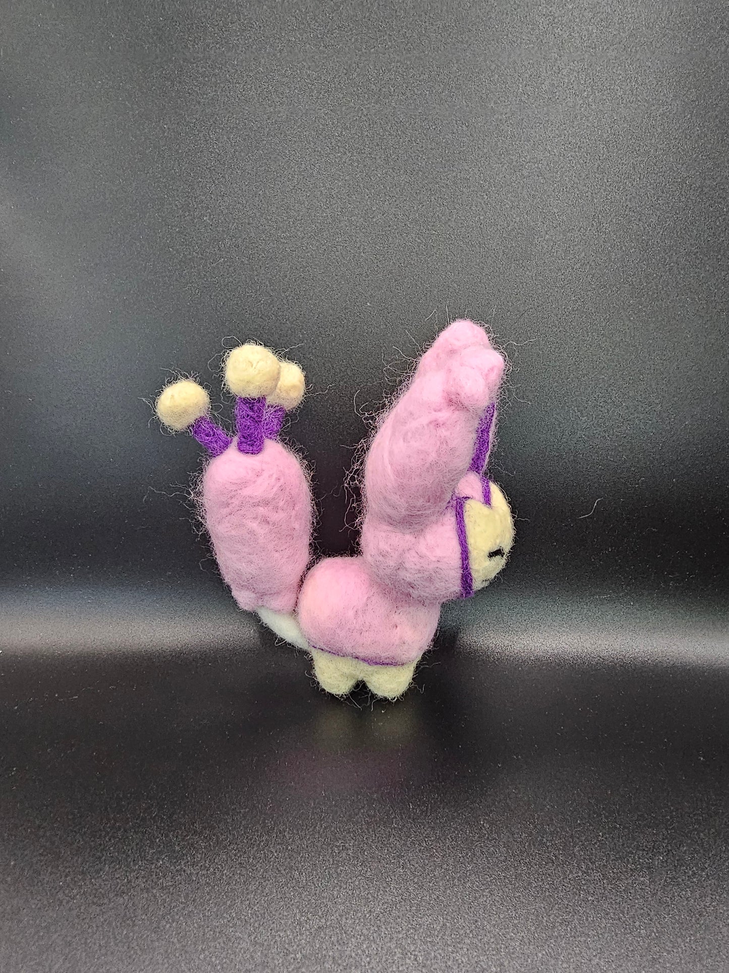 Skitty is a a pink cat with tall ears and a tail that looks sort of like a balloon on a string, with more balloons hanging from it. Features are outline with purple, and interior of ears is purple.