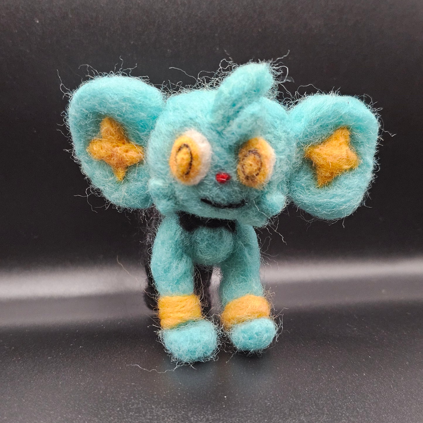 Skitty is a a pink cat with tall ears and a tail that looks sort of like a balloon on a string, with more balloons hanging from it. Features are outline with purple, and interior of ears is purple.