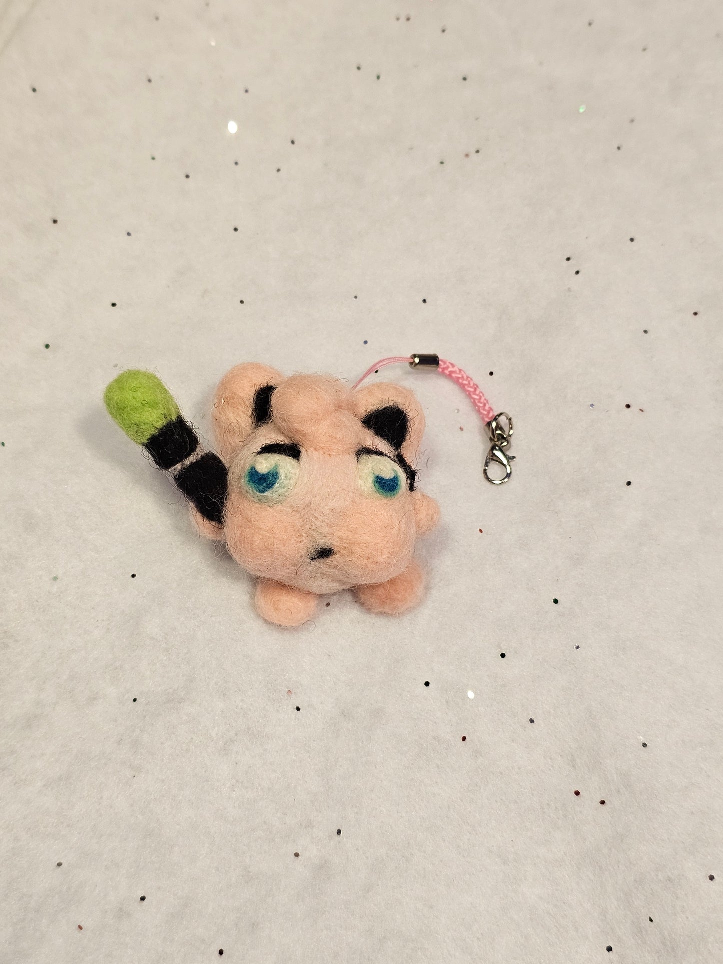 Jigglypuff is a small pink balloon-type pokemon with pointed cat ears. In its angry state, Jigglypuff puffs out it's cheeks and has a vain pulsing in its temple. Jigglypuff has blue eyes and is holding a microphone with a green cover. This photo is straight on.