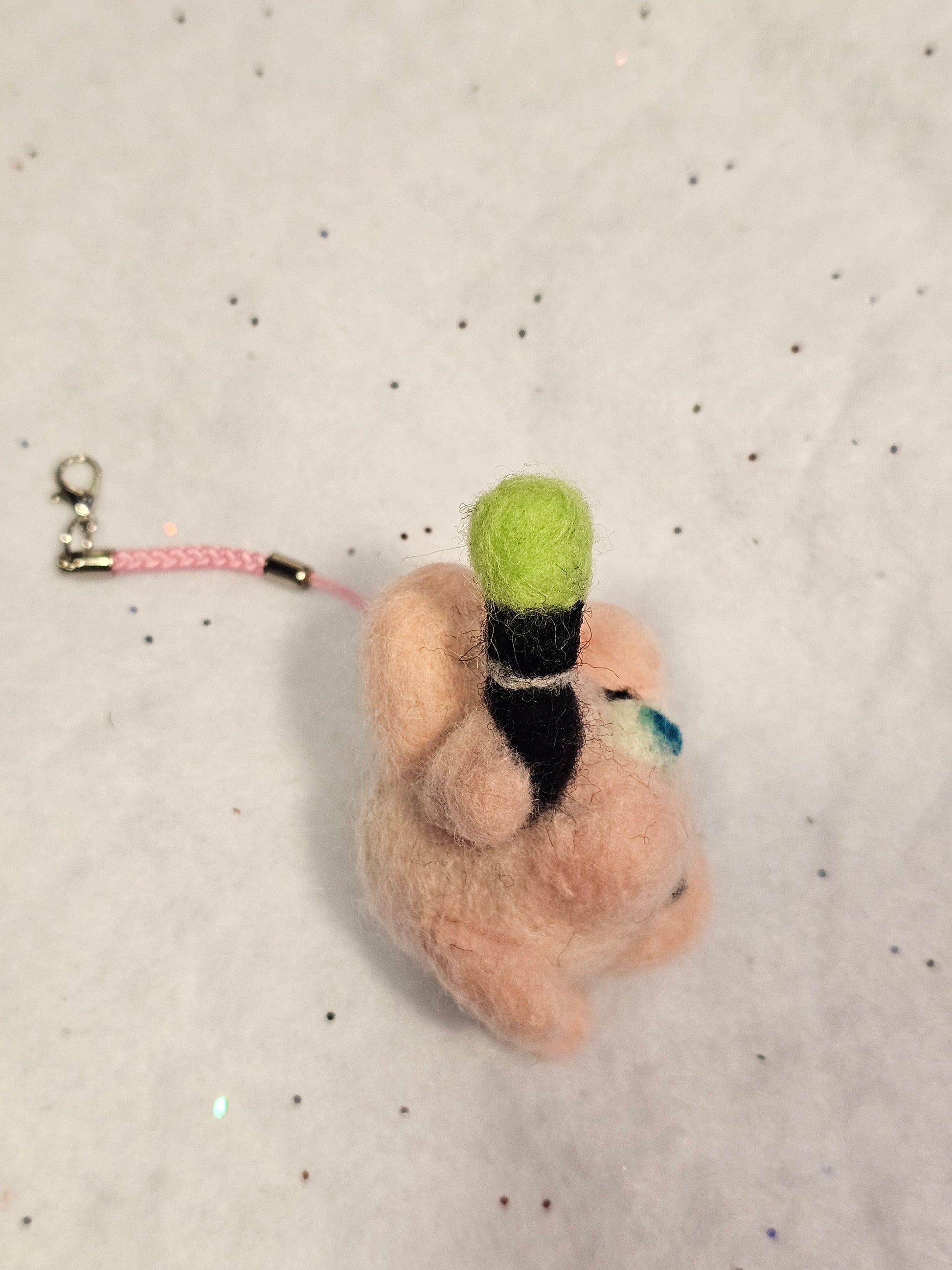 Jigglypuff is a small pink balloon-type pokemon with pointed cat ears. In its angry state, Jigglypuff puffs out it's cheeks and has a vain pulsing in its temple. Jigglypuff has blue eyes and is holding a microphone with a green cover. This photo shows the right profile and a closer view of Jigglypuff's microphone.