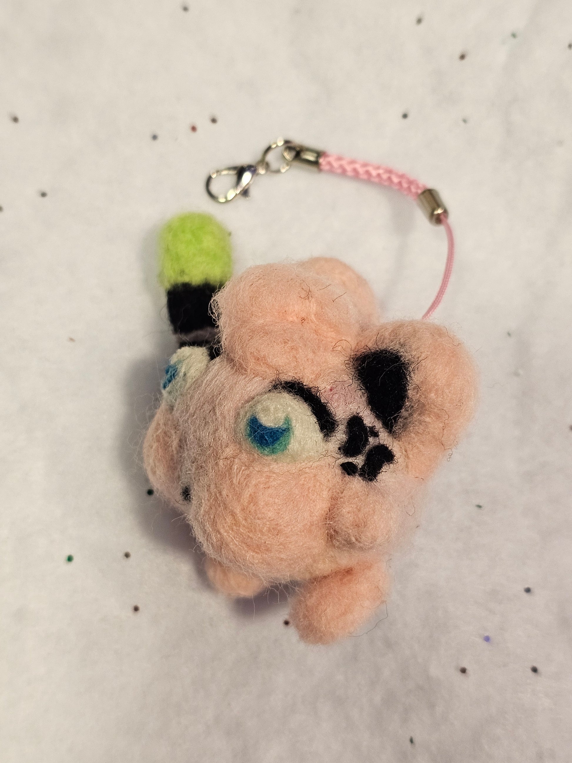 Jigglypuff is a small pink balloon-type pokemon with pointed cat ears. In its angry state, Jigglypuff puffs out it's cheeks and has a vain pulsing in its temple. Jigglypuff has blue eyes and is holding a microphone with a green cover. This photo shows the left profile.